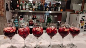Een bar met verschillende flessen en glazen rode drank.
