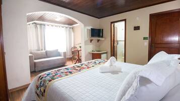 Una habitación de hotel con una cama, televisor, escritorio, silla y sofá.