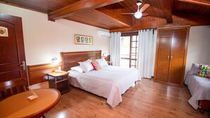 A cozy bedroom with a wooden ceiling, a bed with white bedding, a nightstand, a wooden chair, a small table, and a wardrobe. - Pousada do Bosque (Canela)