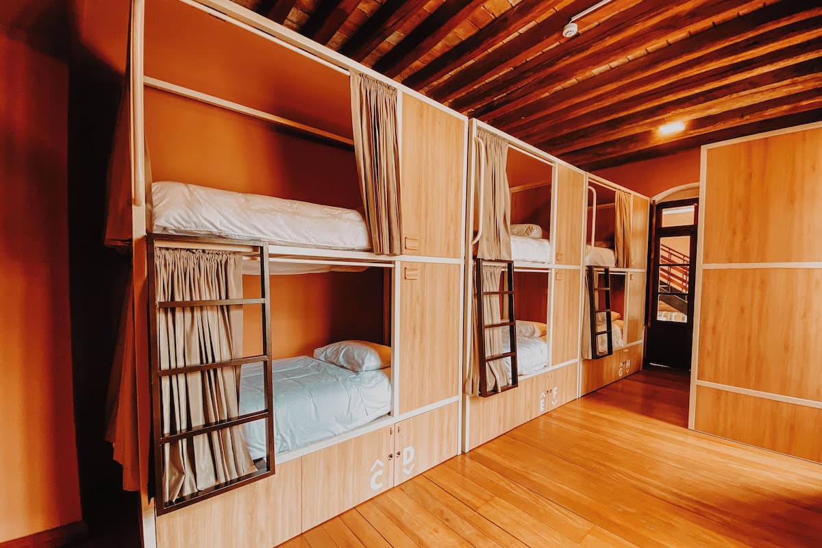 A room with bunk beds, wooden walls, and a wooden floor.