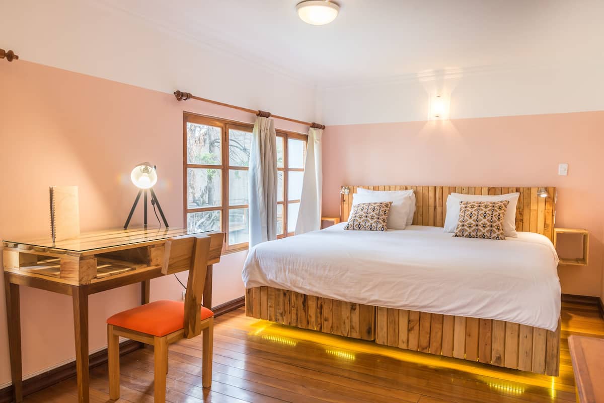 A bedroom with a wooden bed, a desk, and a chair.