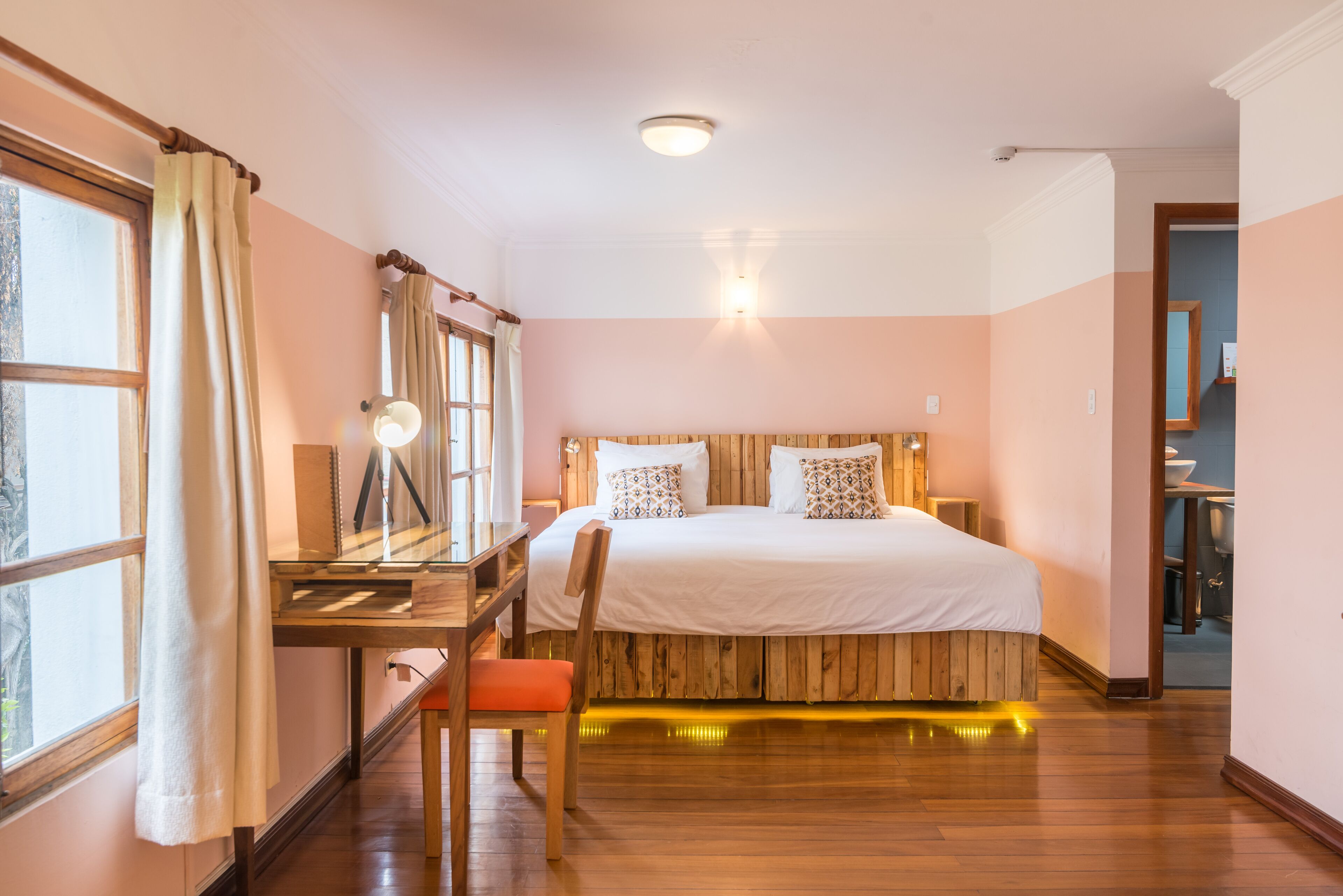 Un dormitorio con una cama de madera, un escritorio y una silla.