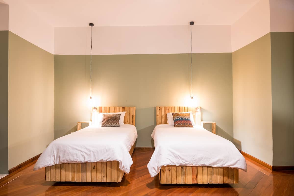 A room with two wooden beds, each with a white bedspread and a patterned pillow.