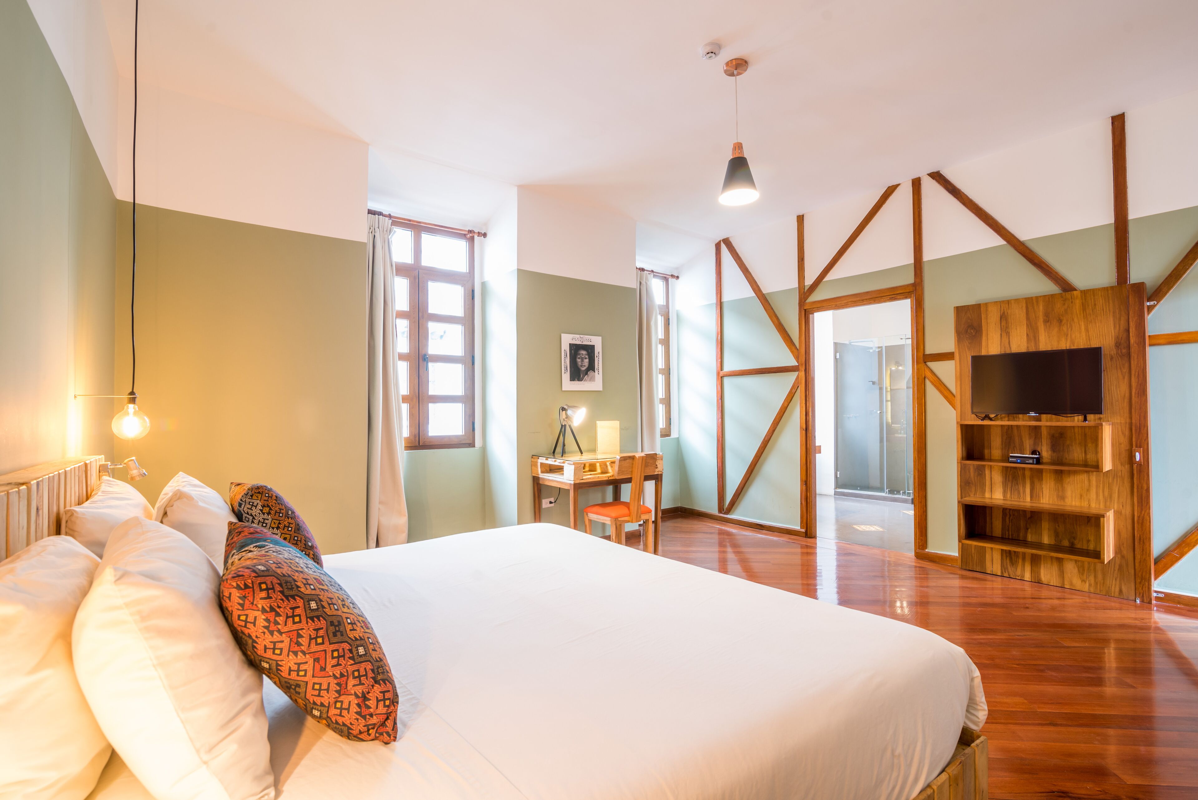 Um quarto espaçoso com uma cama grande, uma escrivaninha e uma estante para televisão.