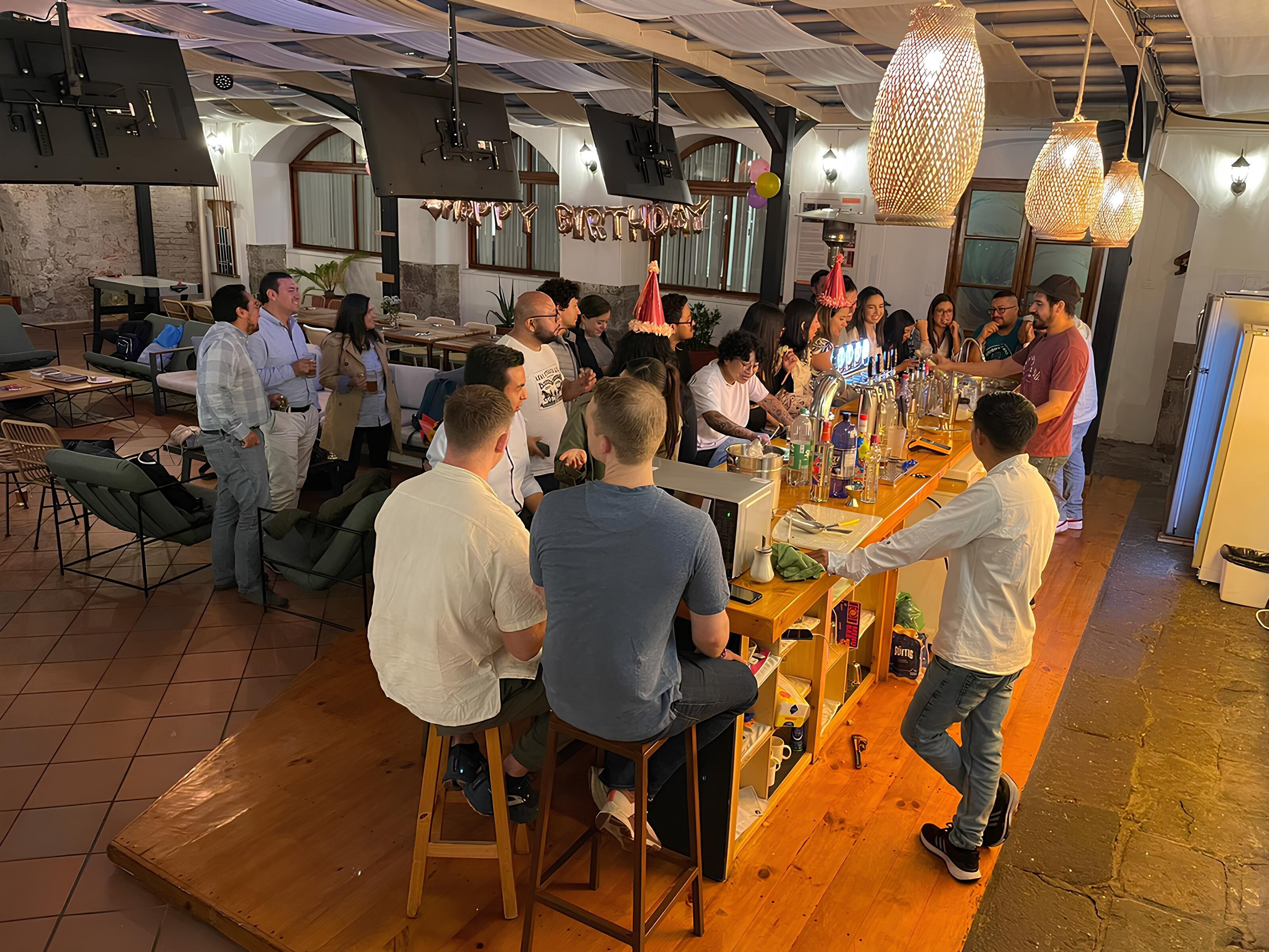 A bar area with stools, a bar counter, and hanging lights.