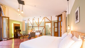 A spacious bedroom with a large bed, wooden headboard, and a wooden-framed window. There is a desk with a chair and a mirror in the room. - Viajero Quito Hostel (Quito)