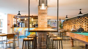 A bar area with stools, a pool table, and a brick pillar. - Viajero Quito Hostel (Quito)