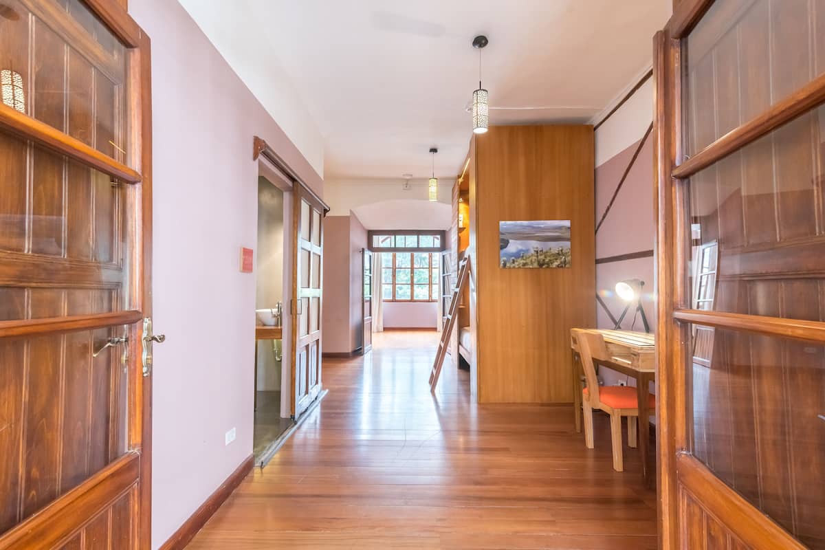 A hallway with wooden doors, a desk with a chair, and a painting on the wall.