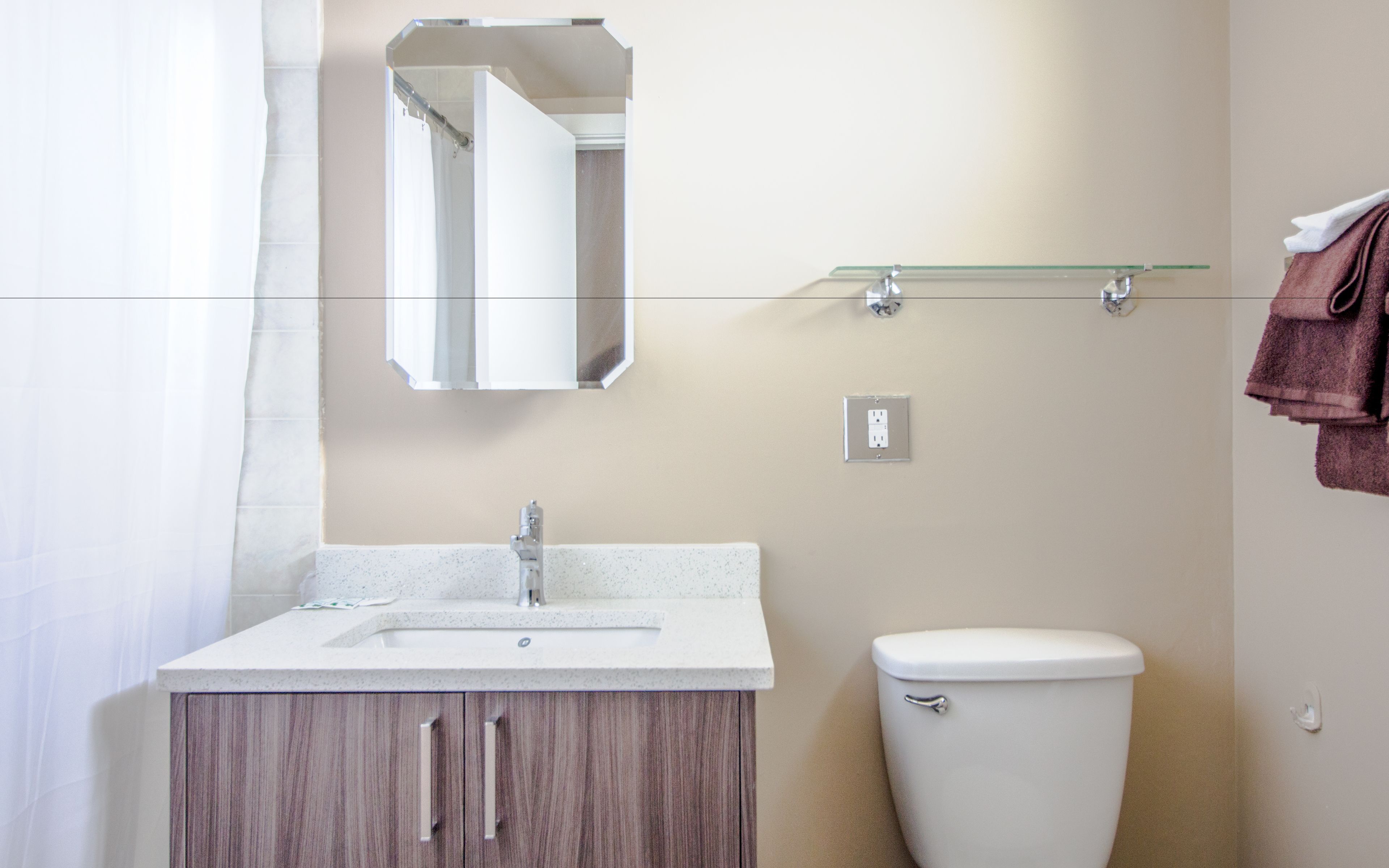 A bathroom with a sink, mirror, toilet, and towel rack.