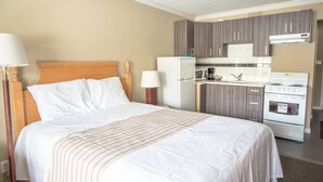 Een hotelkamer met een bed, bedlampen, een koelkast, een magnetron, een kookplaat en een kleine keukenunit.