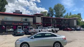 Ett hotell med en skylt som visar namnet ”Okanagan Royal Park Inn” och en parkeringsplats med flera bilar.