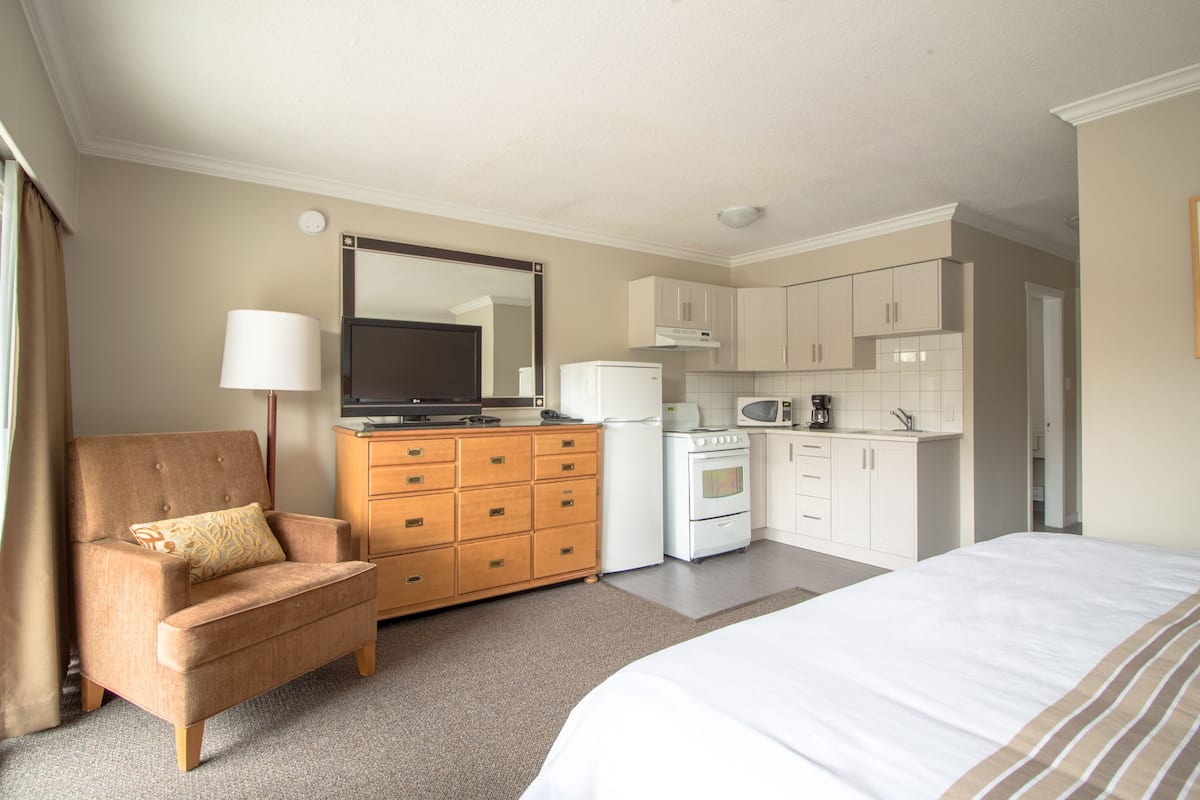 Une chambre d’hôtel comprenant un lit, un canapé, une commode, une kitchenette et un grand miroir.