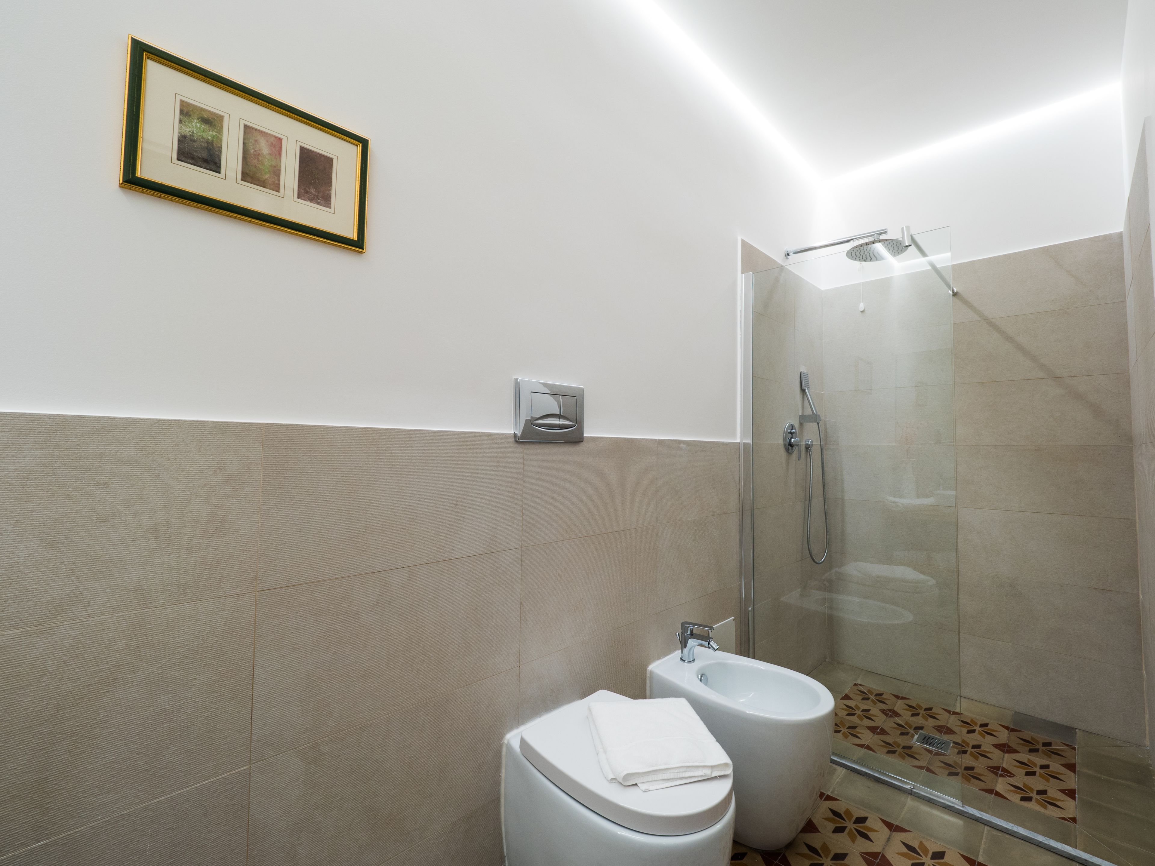 Un baño moderno con cabina de ducha de vidrio, un bidé y un inodoro.
