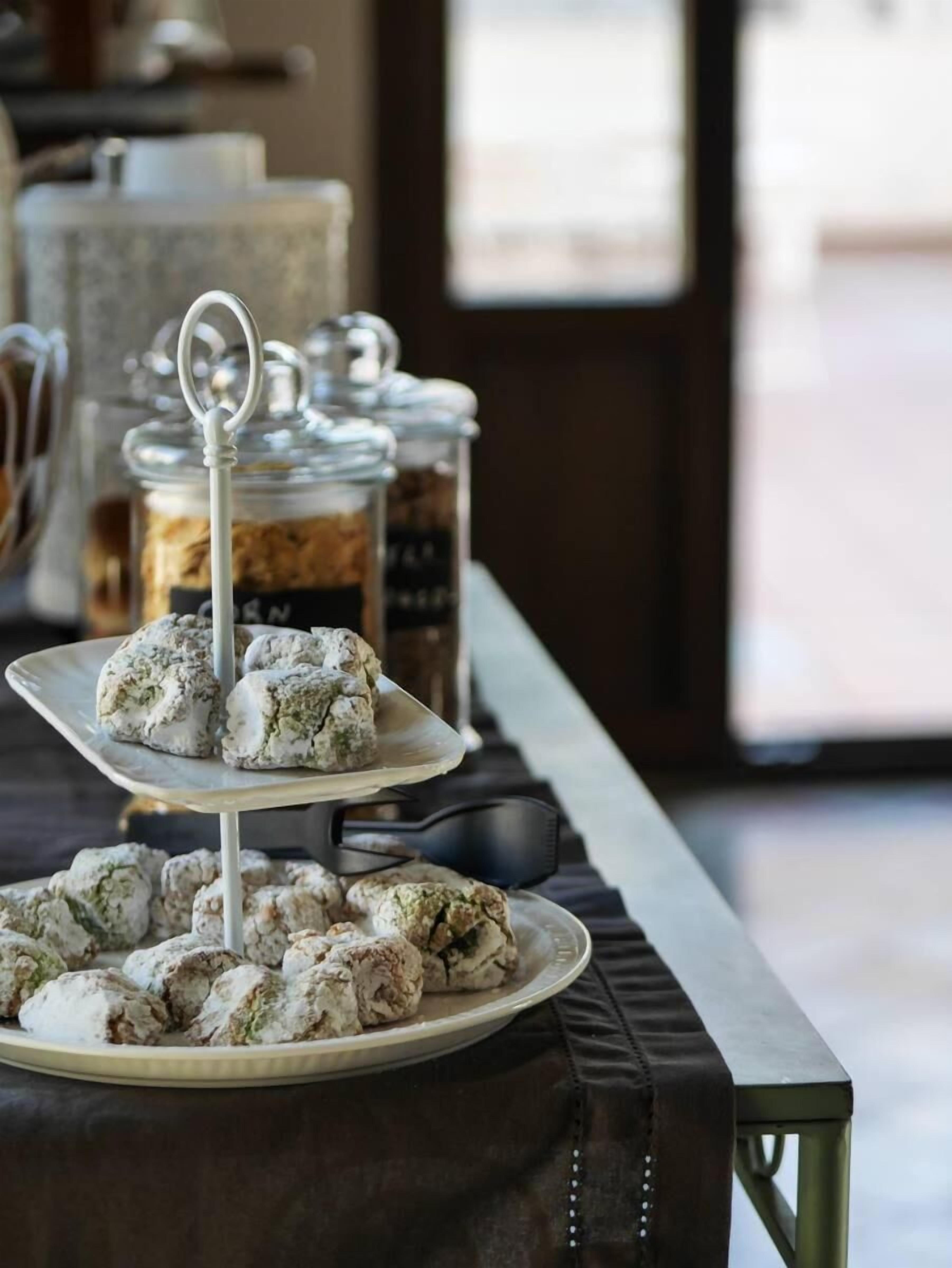 Een buffettafel met drielaagse presentatiebakken vol koekjes, en potten met sauzen op de achtergrond.