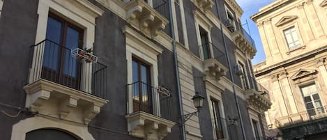 A multi-story building with balconies, arched windows, and a street lamp.