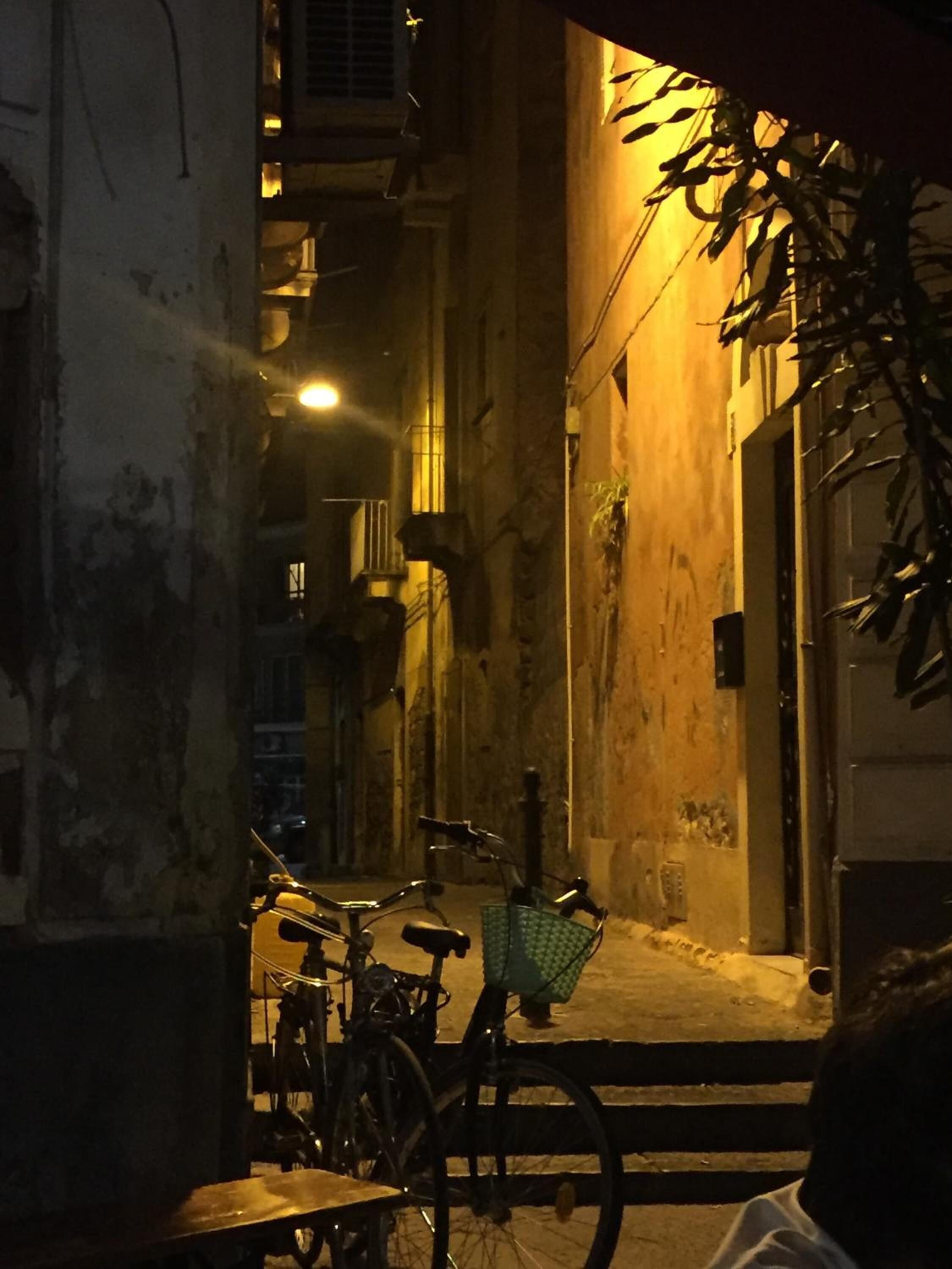 Un callejón estrecho con una bicicleta estacionada al lado, una silla y una mesa.
