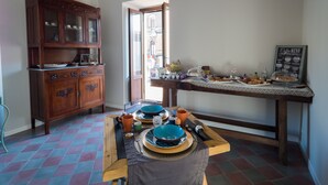 A dining area with a wooden cabinet, a table set with plates, bowls, and cups, and a coffee menu on the wall. - Sciara Larmisi (Catania)