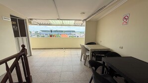 A balcony with a table and chairs, a view of buildings, and a 'No Smoking' sign. - Hostal Posada Del Sol (Guayaquil)