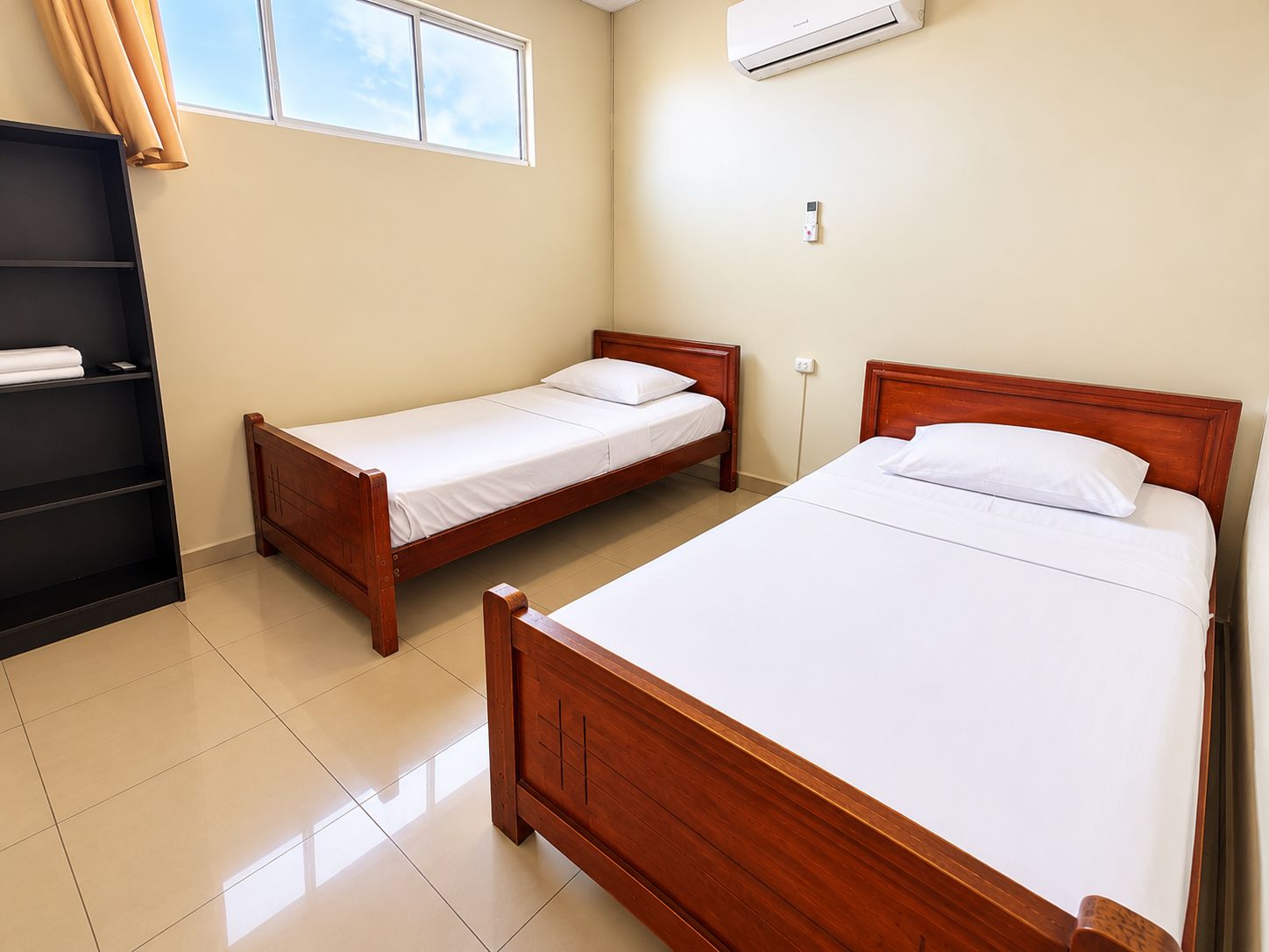 A room with two wooden beds, a black shelf, and an air conditioning unit.