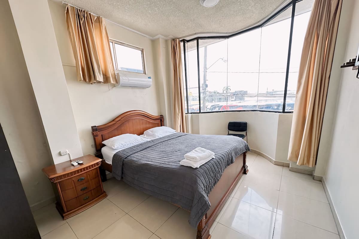 A neatly arranged hotel room with a bed, bedside table, and a window with curtains.