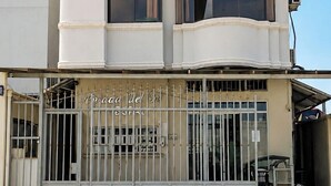 A multi-story building with a gated entrance, large windows, and a sign indicating a hotel. - Hostal Posada Del Sol (Guayaquil)