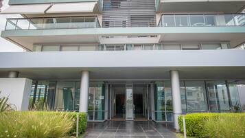 A modern building with a glass entrance, multiple floors, and a covered walkway.