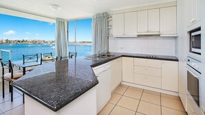 Cozinha com uma ilha grande, armários brancos e vista para o mar.