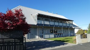 A two-story building with a metal roof, a gated entrance, and a paved driveway. - Mackenzie Lodge (Twizel)