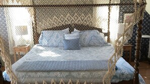 A bed with a canopy and a wooden headboard, a nightstand, and a patterned wall. - Gardenview Bed and Breakfast (Newport)