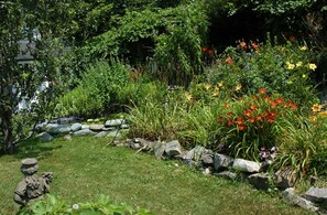 A garden with a variety of plants and flowers, a stone pathway, and a statue. - Gardenview Bed and Breakfast (Newport)