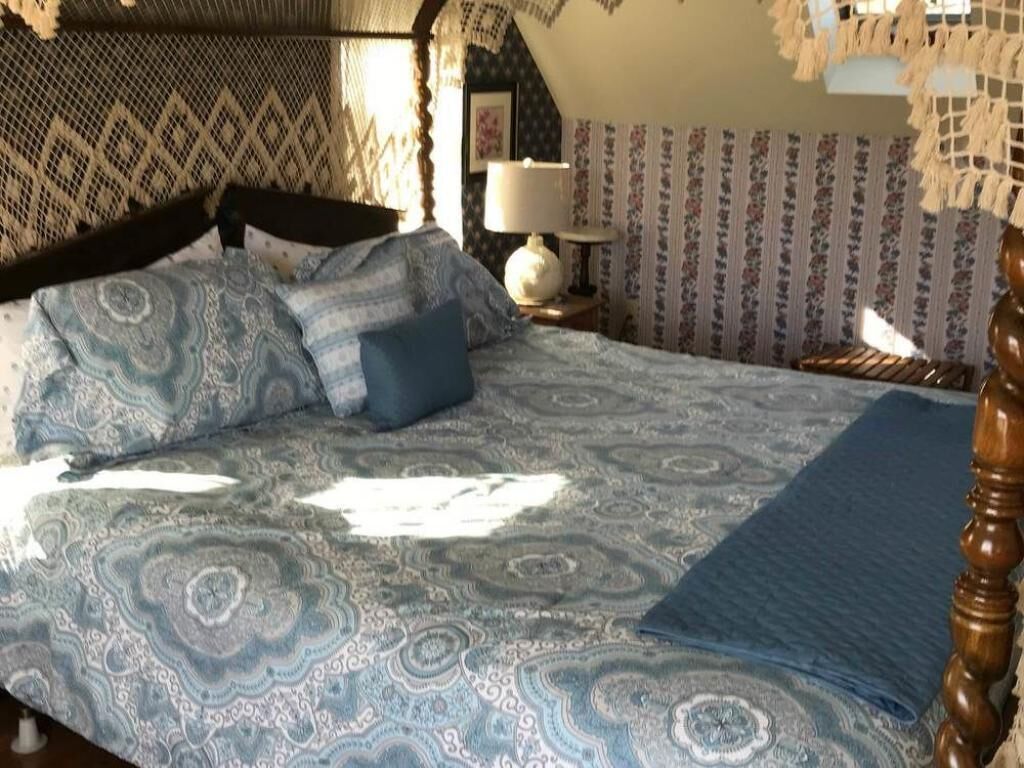Ein Schlafzimmer mit einem gemusterten Bettbezug, einem blauen Kissen und einem Holzkopfteil.