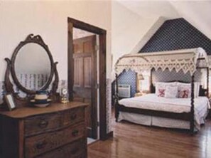 A bedroom with a wooden dresser, a mirror, and a bed with a canopy. - Gardenview Bed and Breakfast (Newport)