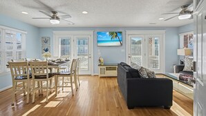 A spacious living area with a dining table, chairs, a sofa, and a television. - Private pool and gorgeous beach house, steps from the ocean! (Surfside Beach)