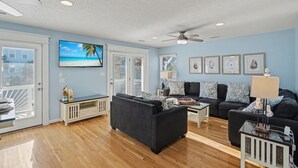A living room with a TV, sofas, a coffee table, and artwork on the walls. - Private pool and gorgeous beach house, steps from the ocean! (Surfside Beach)