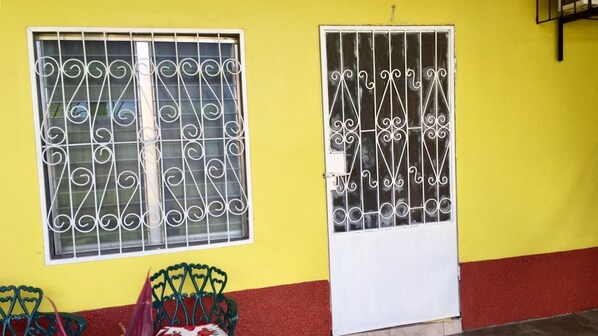 A yellow building with two windows and a door, both featuring decorative metal grilles. - TELA BEACH GETAWAY ☆ Apt #1 (Tela)
