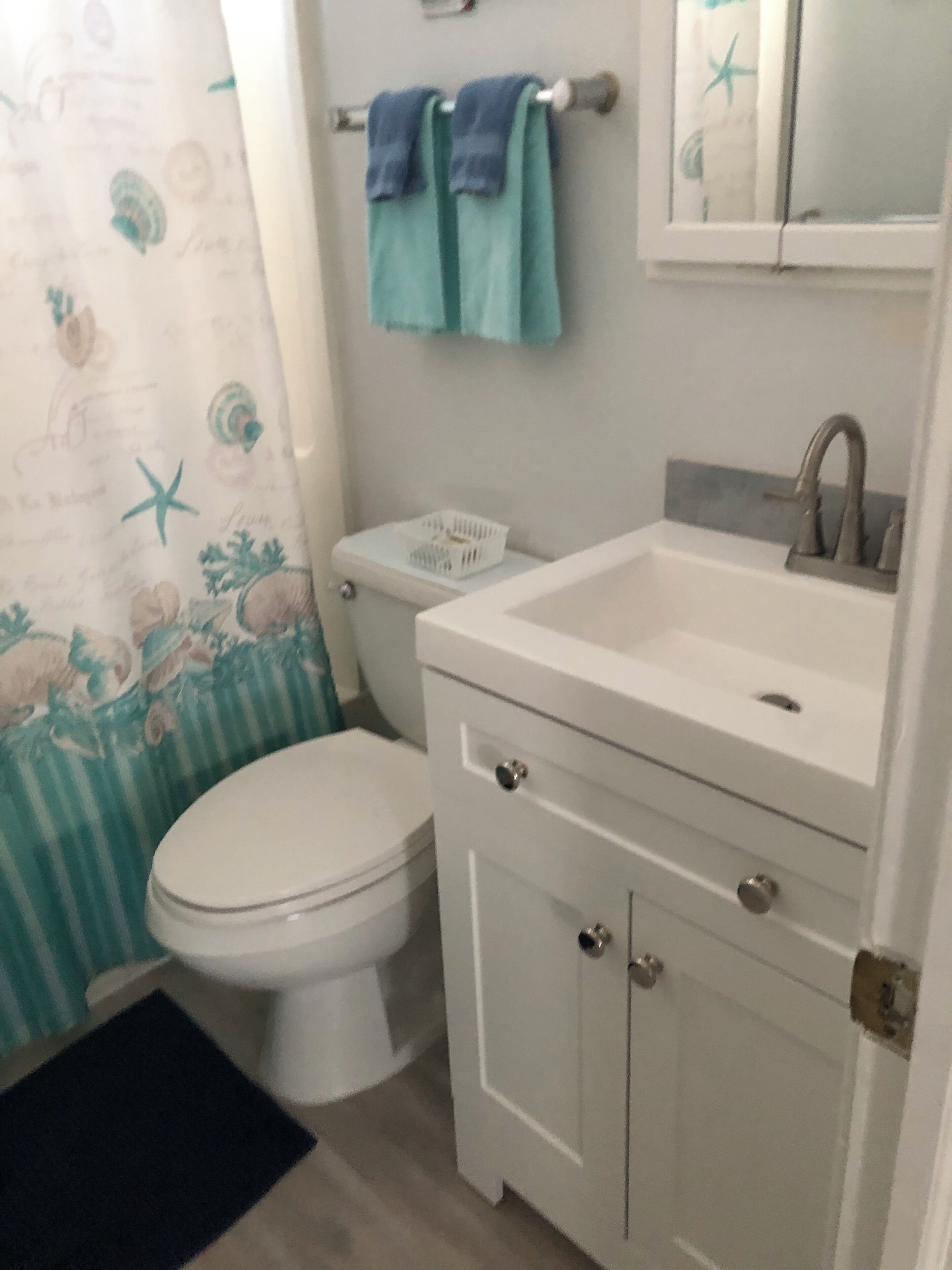A bathroom with a toilet, a sink, and a mirror.