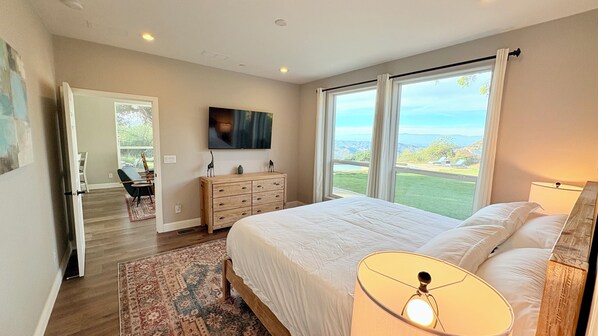 A bedroom with a large bed, a TV mounted on the wall, a dresser, and a view of the outdoors. - Cute 3 Bdr Home W/ Pool/Spa & Amazing Views In Malibu Mtns.  15 Min From Beach (Malibu)