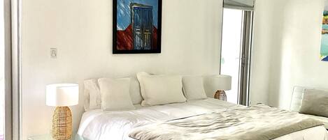 A spacious bedroom with a large bed, a ceiling fan, and a painting on the wall.