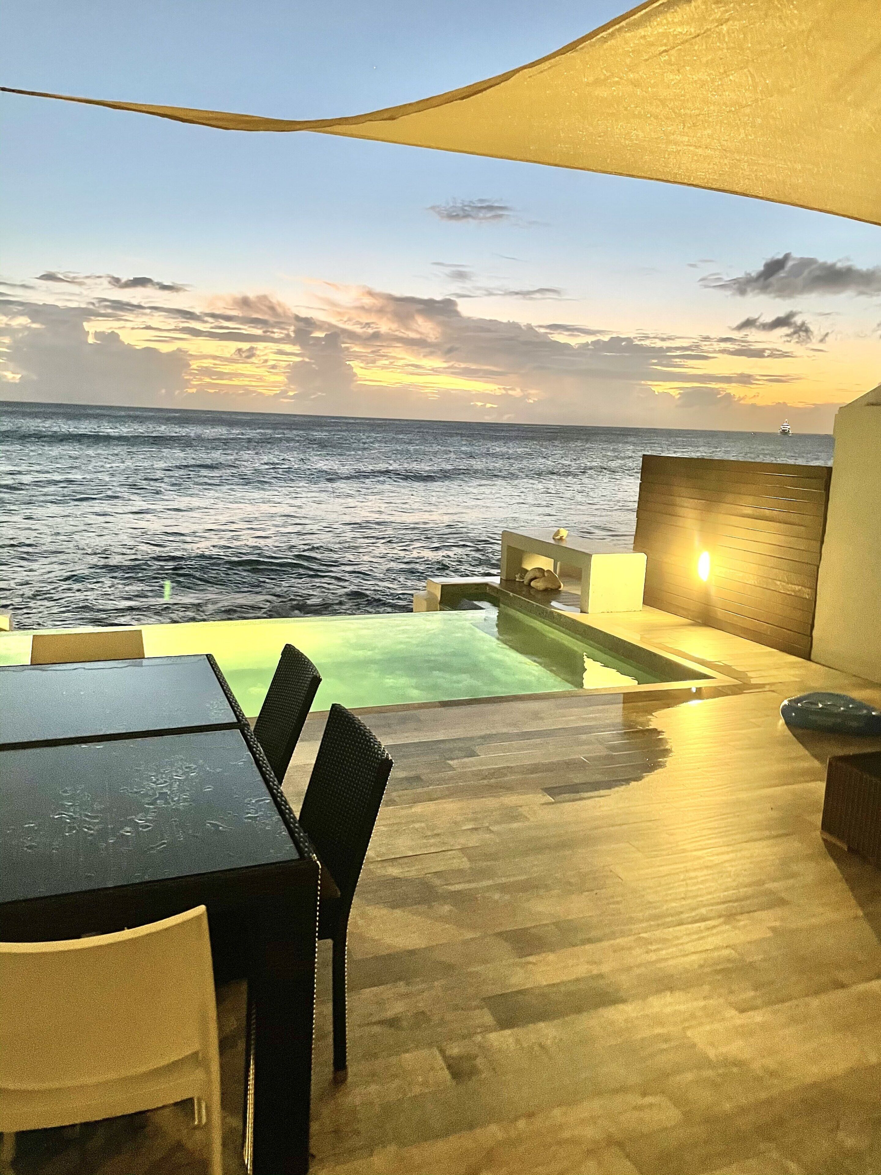 Un espace piscine extérieur offrant une vue sur l’océan et sur le coucher du soleil.