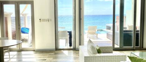 A spacious living area with a view of the ocean, a sliding glass door leading to a balcony, and a modern interior design.