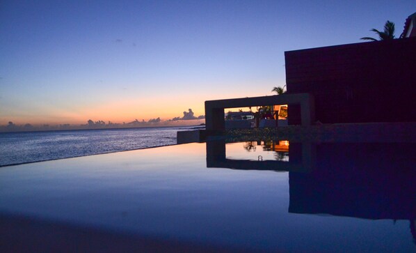 Un bâtiment moderne avec une piscine qui reflète les couleurs du coucher de soleil.
