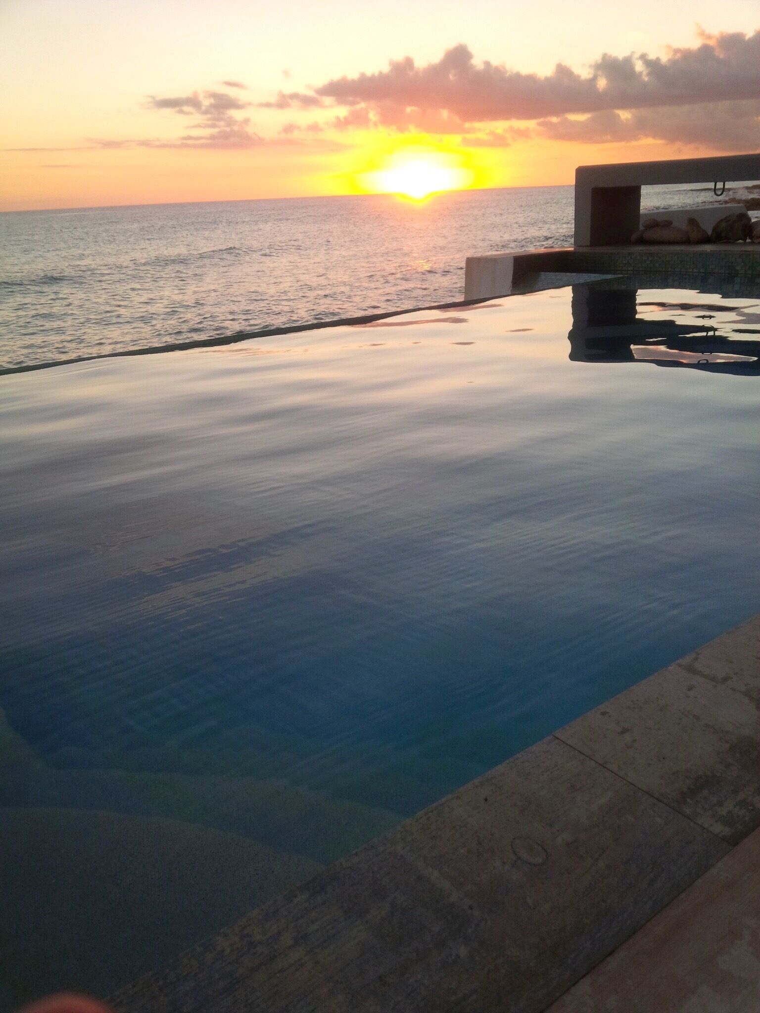 Una piscina infinita con vistas a la puesta de sol sobre el océano.
