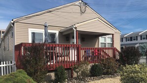 A two-story house with a red deck, a white picket fence, and a gravel driveway. - GORGEOUS BEACH HOUSE, TOP LOCATION! WALK TO BEACH, ICE CREAM, EATERIES. DOGS OK (Brigantine)