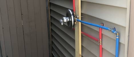 A utility area with a metal gate, a red and blue pipe system, and a wooden post.