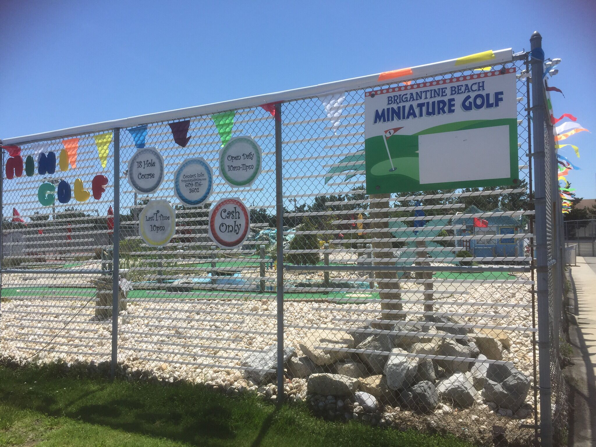 A mini-golf course with a sign indicating it is open daily from 10 am to 4 pm.