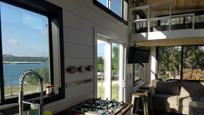 A modern kitchen with a gas stove, a sink, and a window overlooking a body of water.
