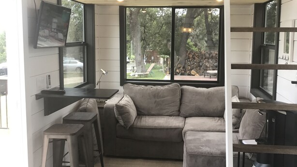 A loft-style room with a sofa, a small table, and a TV mounted on the wall.