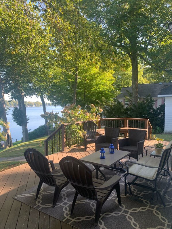 A wooden deck with outdoor furniture and a view of a lake. - Gorgeous Sandy Beachfront Paw Paw lake home with 155 ft. of frontage and dock (Watervliet)