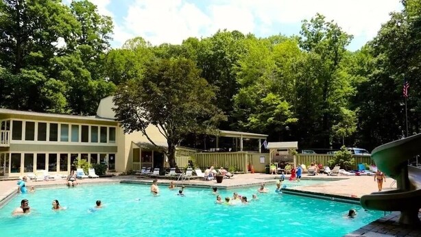 Una piscina rodeada de árboles y un edificio con varias ventanas.