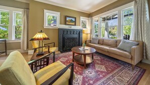 A living room with a fireplace, a sofa, a coffee table, and a patterned rug. - Historic Craftsman Bungalow, Just Steps to Downtown ~HOT TUB!~ (Bend)